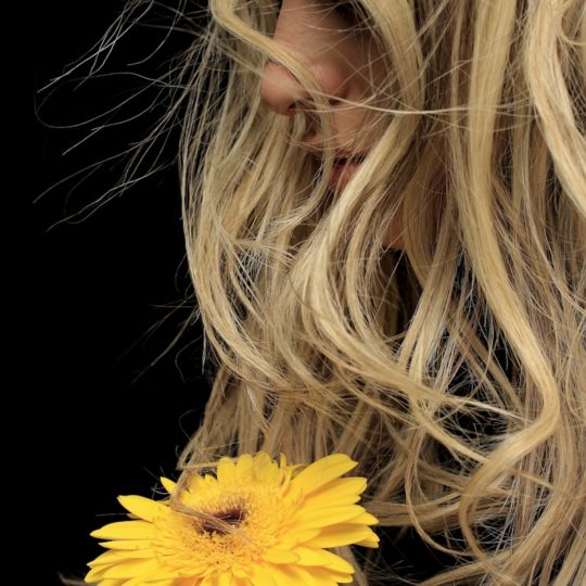 woman with blonde hair holding yellow flower
